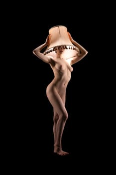 Full body of graceful nude slim female model holding lampshade over head - live lamp stand concept