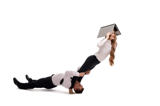 Cooperation concept studio shot of businessman supporting legs of female coworker using laptop on white background