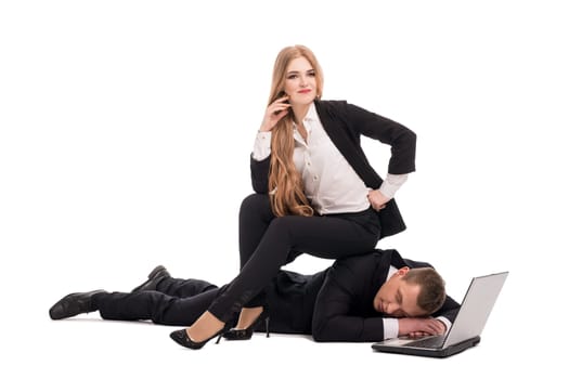 Female entrepreneur in suit sitting on back of exhausted businessman near modern netbook against white background