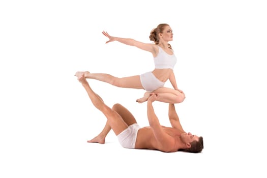 Full body side view of strong shirtless muscular man supporting female partner performing graceful acrobatic movement isolated on white background