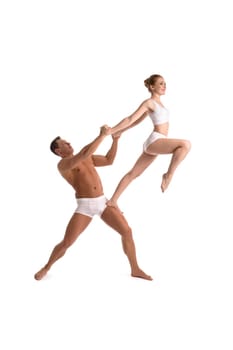 Full body side view of strong shirtless muscular man supporting female partner performing graceful acrobatic movement isolated on white background
