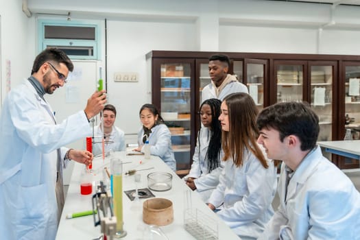 Multi ethnic group of students wearing lab coats attending a chemistry class, teacher making experiment in university laboratory