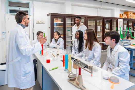 Chemistry teacher holding a test tube and explaining experiment to students sitting at desk in university laboratory