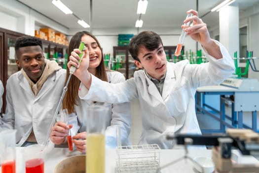 Young chemistry students wearing lab coats performing experiment using test tubes and other laboratory equipment