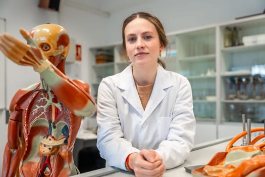 Young scientist standing in university laboratory with anatomical models, studying human body and physiology