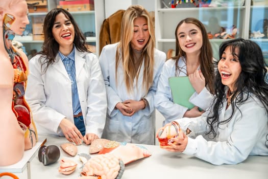 Four cheerful medical students examining anatomical models and having fun during an anatomy class in university lab