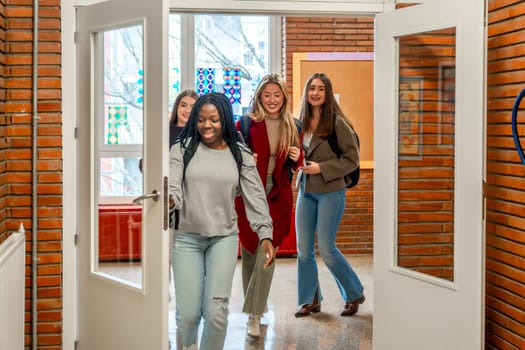 Cheerful female students are walking out of the classroom after their lesson at the university
