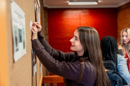Female college student pinning an important notice on a bulletin board in a busy campus hallway, actively engaging with her community