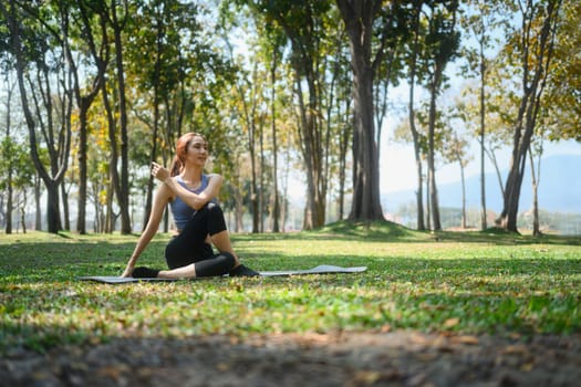 Young woman practicing yoga practicing yoga in nature, sitting in Half lord of the fishes pose.