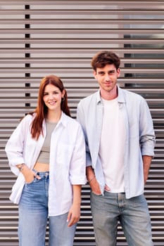 man and woman standing next to each other smiling looking at camera, both are wearing white shirt and jeans, they seem to be enjoying each other's company, concept of couple and urban lifestyle