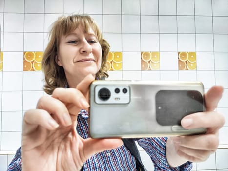 A middle-aged woman smiles while capturing a selfie in the mirror, showcasing her morning routine and lifestyle.