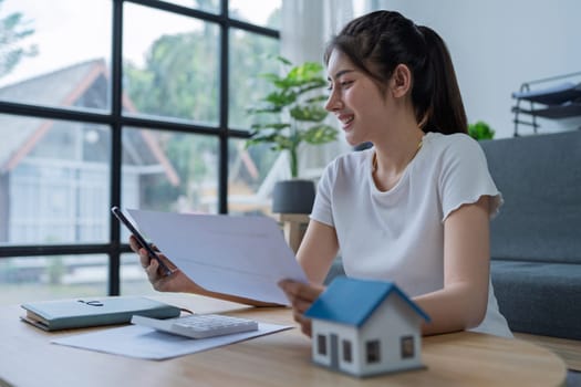 Young woman engaged in a phone conversation while working on home finances in a cozy modern living room.