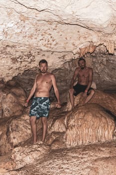 Mean male tourists friends are posing and climbing in the turquoise green blue water and rocks in cenote Yaxmulito in Tulum Quintana Roo Mexico.