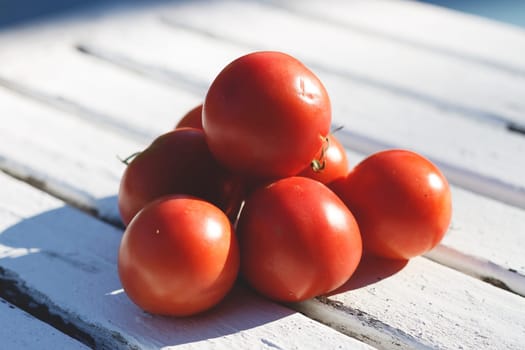 A visually appealing composition of fresh red tomatoes stacked together on a rustic wooden surface, showcasing their vibrant color and organic texture.