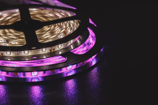This image showcases a close-up view of a coil of LED strip lights glowing vividly in purple hues, set against a dark background, emphasizing their energy-efficient design.