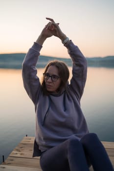 Woman sitting on the pier, closeup portrait, summer sunset