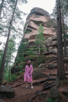 Woman in raincoat in the taiga forest and rocks of the Stolby nature reserve park, Krasnoyarsk, Russia