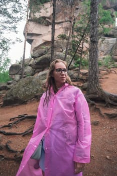 Woman in raincoat in the taiga forest and rocks of the Stolby nature reserve park, Krasnoyarsk, Russia