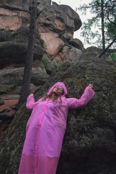 Portrait of woman in the raincoat the taiga forest and rocks of the Stolby nature reserve park, Krasnoyarsk, Russia