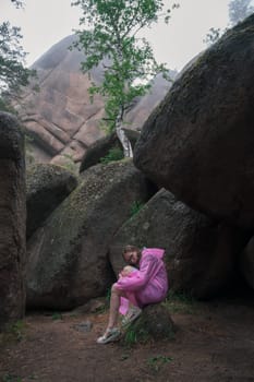Woman in raincoat in the taiga forest and rocks of the Stolby nature reserve park, Krasnoyarsk, Russia