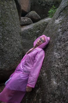 Portrait of woman in the raincoat the taiga forest and rocks of the Stolby nature reserve park, Krasnoyarsk, Russia