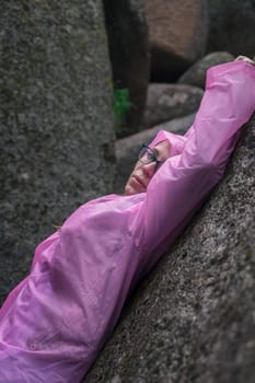 Portrait of woman in the raincoat the taiga forest and rocks of the Stolby nature reserve park, Krasnoyarsk, Russia
