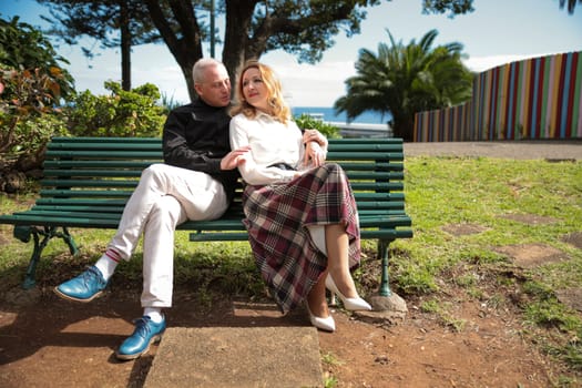Mature couple enjoying sunny day on a bench in a park in funchal, madeira