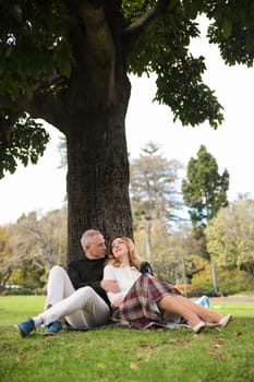 Mature couple enjoying a romantic moment together, sitting under a tree in a picturesque park