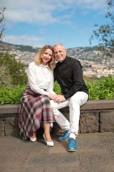 Cheerful couple holding hands, embracing and enjoying scenic view of funchal cityscape during their vacation in madeira