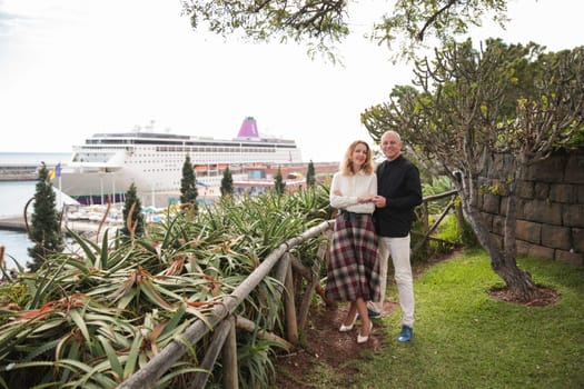 Tourists posing in a garden overlooking the harbor with a cruise ship docked in funchal, madeira island, portugal