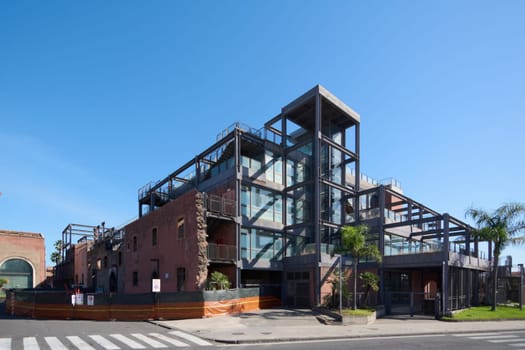 Catania. Italy - February 25, 2025: Industrial building with exposed metal and glass design, palm trees in the foreground, and a clear blue sky. Concept: modern architecture, industrial design.