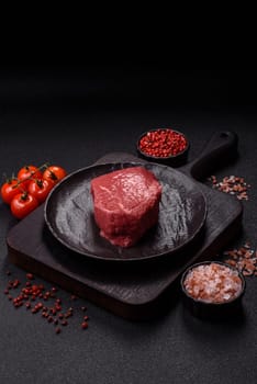 Raw beef tenderloin ribeye steak with salt and spices on a dark concrete background