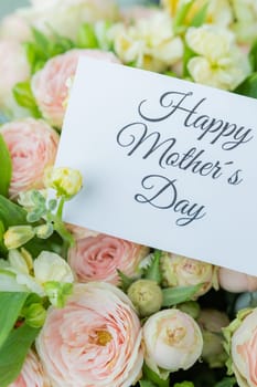 Amazing tender bouquet with pink ranunculus, violet Alstroemeria flowers and tiny white roses in cardboard box with pink ribbon. Beautiful bunch of spring flowers. Easter gift. Seasonal spring flowers