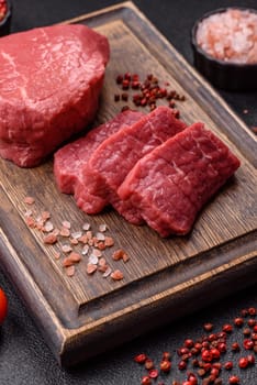 Raw beef tenderloin ribeye steak with salt and spices on a dark concrete background