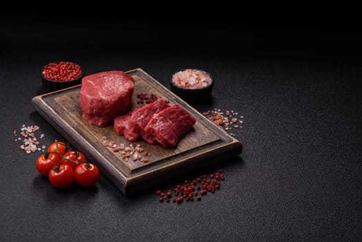 Raw beef tenderloin ribeye steak with salt and spices on a dark concrete background