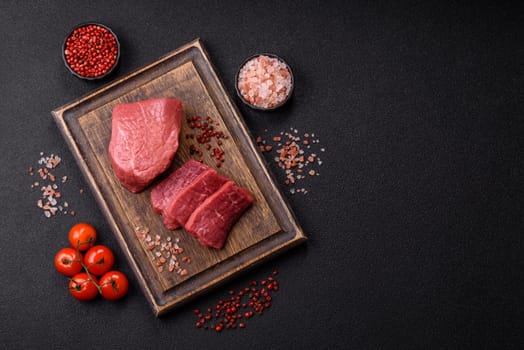 Raw beef tenderloin ribeye steak with salt and spices on a dark concrete background