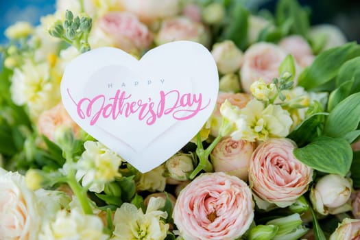 Amazing tender bouquet with pink ranunculus, violet Alstroemeria flowers and tiny white roses in cardboard box with pink ribbon. Beautiful bunch of spring flowers. Easter gift. Seasonal spring flowers