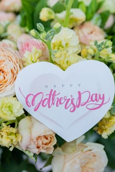 Amazing tender bouquet with pink ranunculus, violet Alstroemeria flowers and tiny white roses in cardboard box with pink ribbon. Beautiful bunch of spring flowers. Easter gift. Seasonal spring flowers