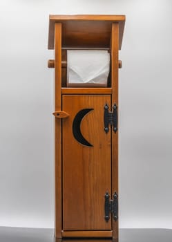 This wooden bathroom cabinet stands upright, featuring a moon-shaped cutout and a tissue holder on top. Its natural wood finish and sleek design make it a stylish storage solution.