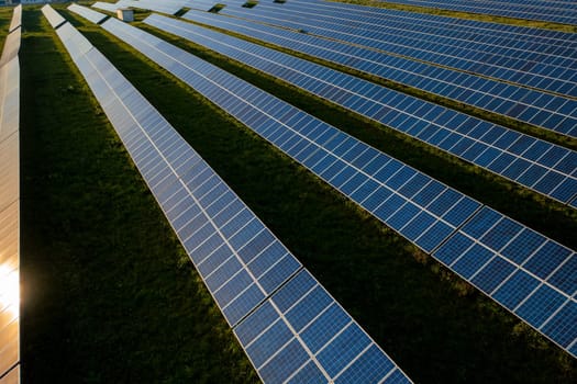 Drone view of blue solar panels on agricultural field during sunny day. The landscape is fully equipped with green renewable energy generators
