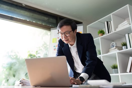 An elderly financial analyst presents insights from budget charts in a modern office, focusing on strategic financial planning and analysis.