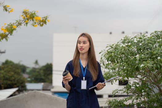 A cheerful healthcare professional enjoys her break while writing notes and sipping coffee in a tranquil outdoor environment.