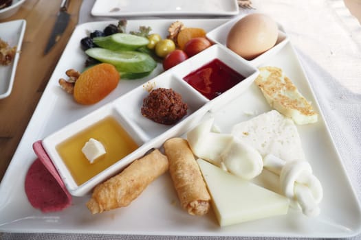 A colorful breakfast platter with cheeses, fruits, and nuts served outdoors.