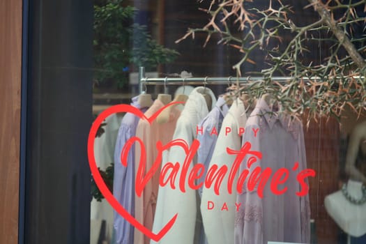 Store window featuring Valentine's Day decorations and stylish clothes.