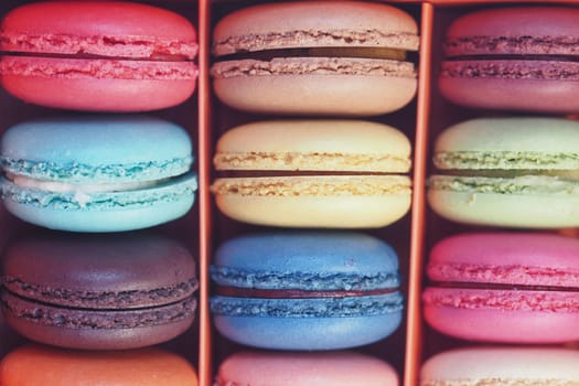 Different flavored macarons arranged in a vibrant box for dessert enjoyment.