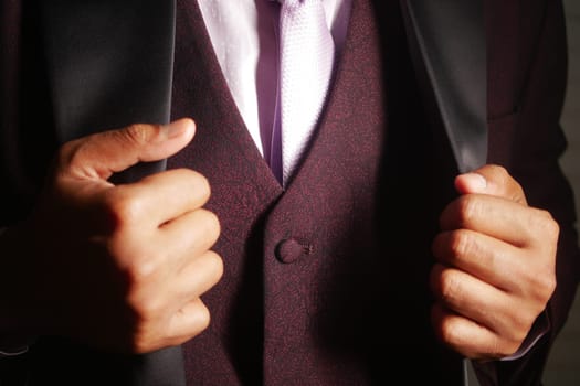 A man adjusts his suit jacket before attending a special event.