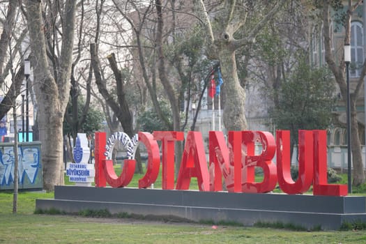 Bold red sign spelling Istanbul stands prominently in park setting.