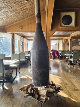 inside home house cafe showing a wood burning heater in the middle of seating area showing how people traditionally kept warm in Gulmarg Kashmir India