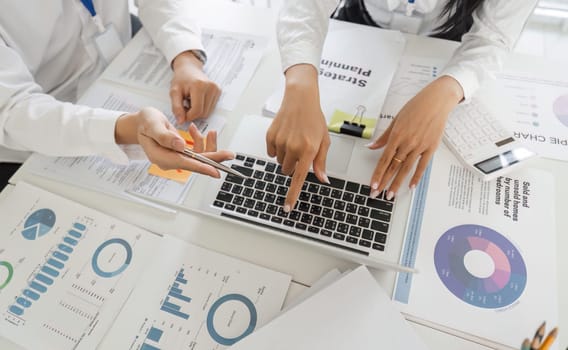 Professionals collaborate on tax strategies, analyzing data displayed on a laptop in a modern office setting.