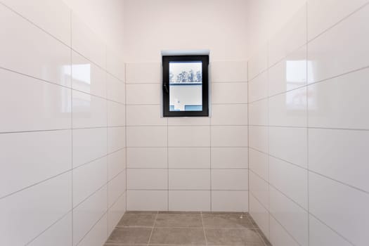 This clean, minimalist room with tiled walls and a large window suits contemporary design aesthetics well